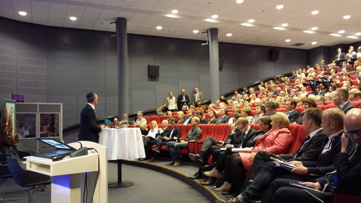 Full auditorium at Felix Conference Centre on Aker Brygge, with a speaker at the lectern and the audience in the hall